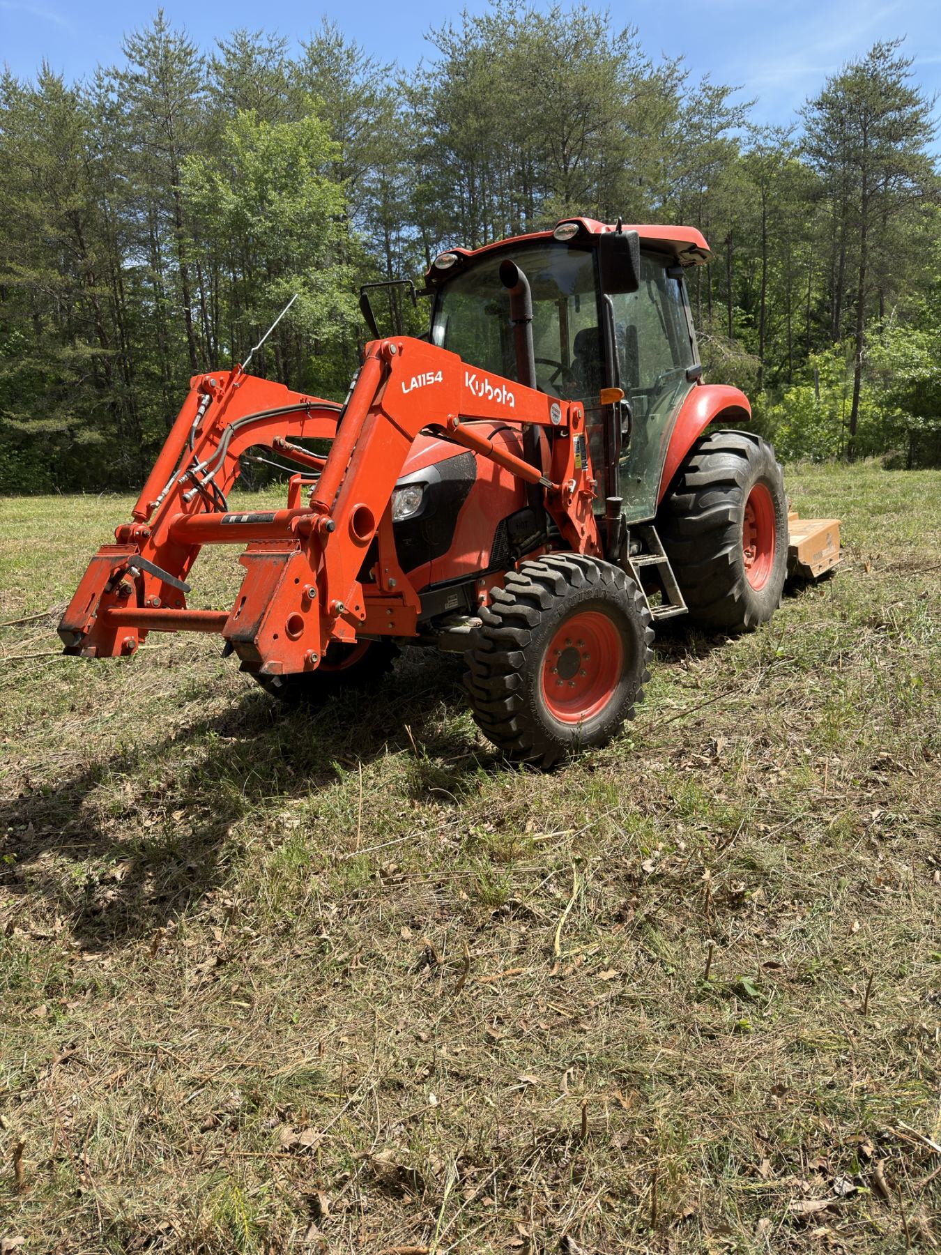 Kubota tractor with bush hog attachment in a field